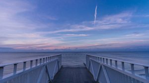 Calm ocean view from a wooden jetty during a beautiful sunset. Perfect for travel inspiration.