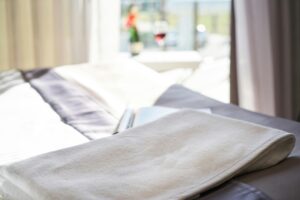 A well-lit modern hotel room with fresh towels and wine, offering a relaxing atmosphere.